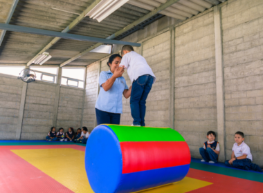 Un niño de 4 años sobre un cilindro acolchado guiado por su maestra.