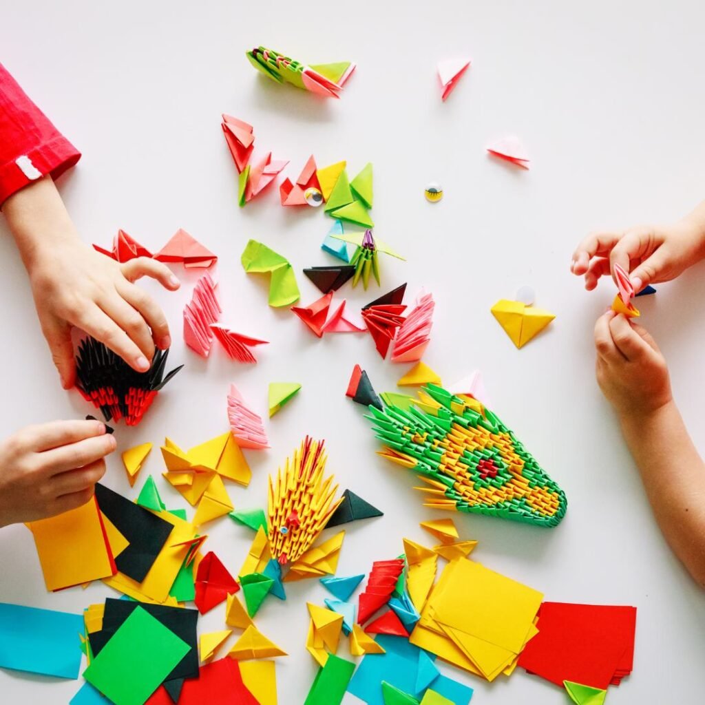 Manos de niños realizando figuras de origami en Colegio Kids World